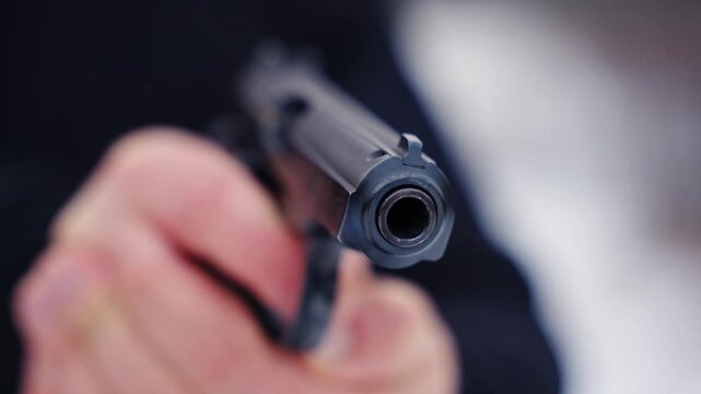 A person pointing a handgun towards the camera, evoking danger and tension