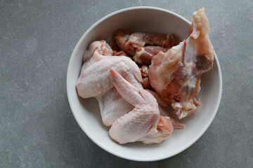 Raw chicken pieces in a white bowl on the counter.
