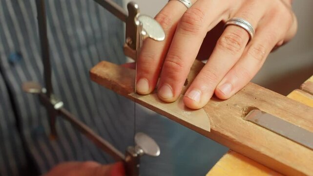 A person saws a piece of wood precisely in a workshop filled with tools and materials.