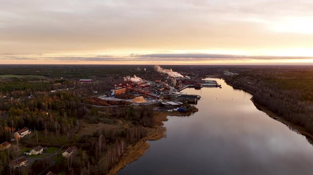 Pulp and paper mill reflecting on calm river at sunset