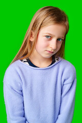 A young child in a light purple sweater gazes against a green background while deep in thought
