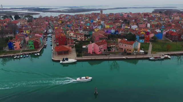 Colorful houses in burano, italy, with a boat in a serene canal, aerial view