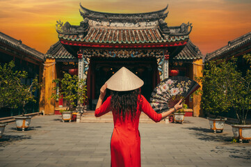 A woman in a traditional Vietnamese dress on the background of an Asian temple in Hoi An