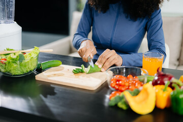 Smiling woman in a modern kitchen with fresh fruits, vegetables, blender, and orange juice, promoting clean