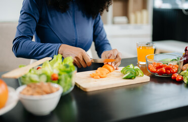 Smiling woman in a modern kitchen with fresh fruits, vegetables, blender, and orange juice, promoting clean