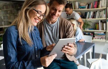 Two young businesspeople using a digital tablet while standing in a boardroom.