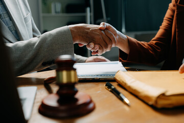 Middle age partner lawyers attorneys shaking hands after discussing a contract agreement done.