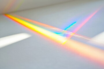 A prism refracts sunlight, casting a vibrant rainbow of colors across a white surface.