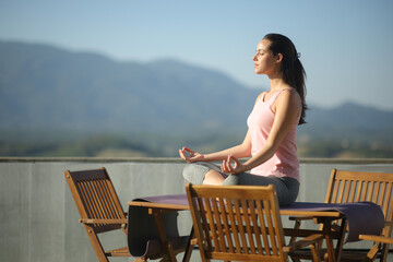Woman doing yoga on a table in a tarrace at home