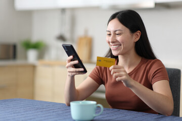 Happy asian woman in the kitchen buying online