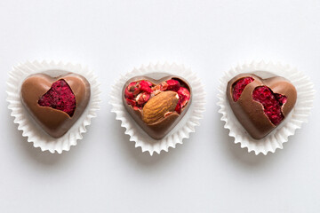 chocolate sweets in the form of a heart with fruits and nuts on a colored background. top view with space for text, holiday concept