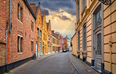 Bruges, Belgium. Antique brick walls along narrow lane with paving stones of old medieval city....