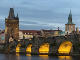 Charles Bridge illuminated at dusk in Prague.