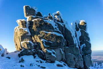 Snow-covered rock formation under blue sky.
