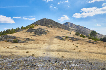 Empty hiking trail along the mountain ridge towards a peak on the distant horizon, in Madrid, Spain