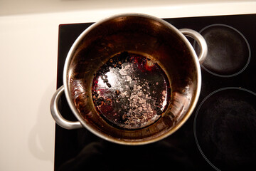 Overhead view of a large burnt pot with chickpeas inside on the induction hob in the kitchen at home