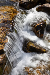 Detail of a small waterfall with water and stones with a silk effect in a river