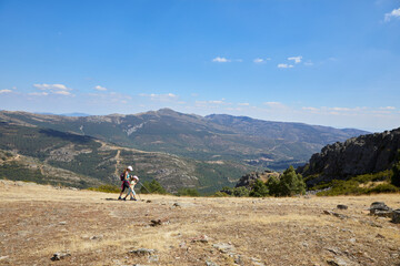 Woman and girl in the distance walking along the mountain over a valley with the horizon in the background, in Madrid, Spain
