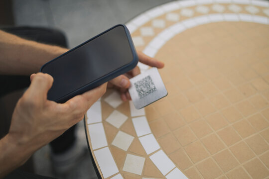 Man scanning QR code with smart phone at restaurant