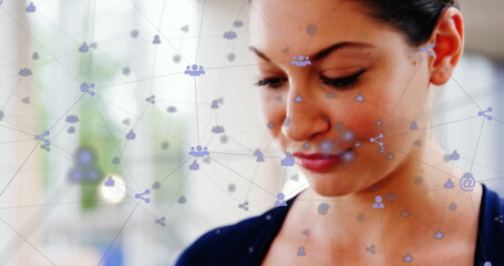 Image of network of connections with digital icons over caucasian businesswoman using smartphone