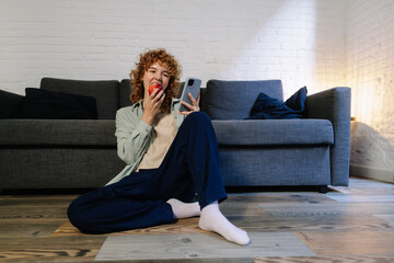 Beautiful woman eating apple and using smartphone at home