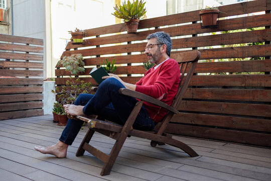 Man sitting on chair and reading book at home