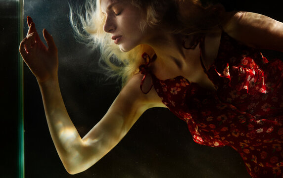 Blond woman with eye closed under water