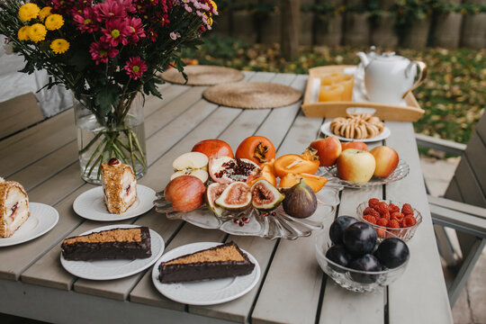 Pastries with fruits and drinks served on table in backyard