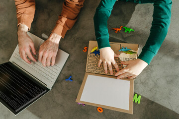 Father using laptop and son playing with toy at home