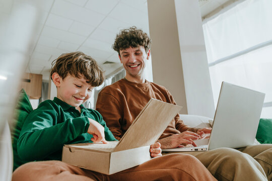 Cute boy playing with toy laptop near father at home