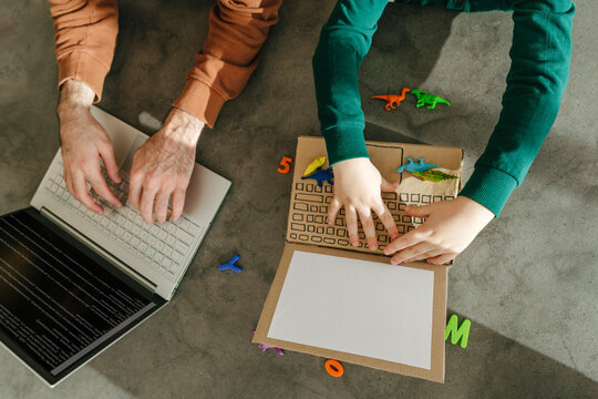 Father using laptop and son playing with toy at home