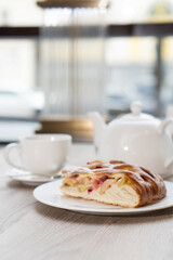 A lush piece of yeast pie with berries in a pastry shop on a table with tea