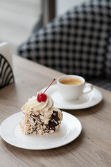 Creamy chocolate cake with and cup of coffee on table in confectionery shop