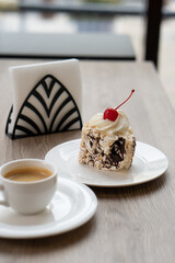 Creamy chocolate cake with and cup of coffee on table in confectionery shop