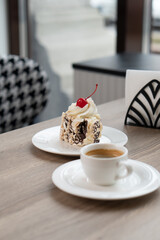 Creamy chocolate cake with and cup of coffee on table in confectionery shop