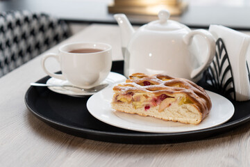 Berry pie piece on plate next to teapot on table in cafe