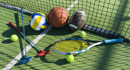 football soccer ball basketball tennis ball and racket laid on grass at sunset