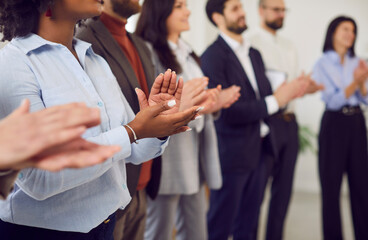 Group of diverse young people applauding standing in a row. Friendly smiling successful coworkers and company employees clapping a colleague on a meeting or business conference. Selective focus.