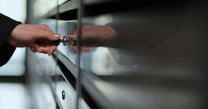 Close up of young woman opening postbox and taking mail. Key opens the mailbox.