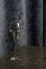 Tall glass with white sparkling wine on a black table in a restaurant