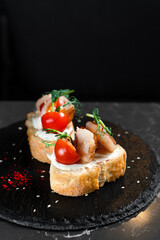 Bruschetta two pieces with shrimps and cherry tomatoes on a black plate
