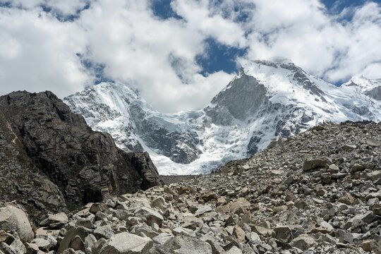 Snow-capped mountains and rocky terrain under cloudy sky.