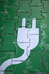 white plug on green stones, symbolizing a charging station for electric vehicles