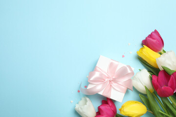 Beautiful fresh tulips with gift box on color background