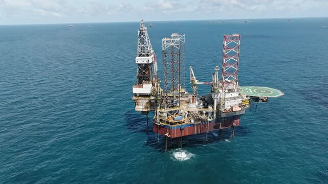 Circling aerial shot of offshore jackup drilling rig, oil and gas industry