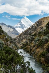 Snow-capped mountain and river in a rocky valley.