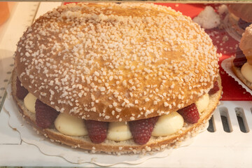 Cake Tarte tropezienne or La Tarte de Saint-Tropez - dessert pastry consisting of filled brioche with cream and fresh red berries