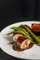 Stuffed rolls and asparagus as decoration. Restaurant dish on a white plate