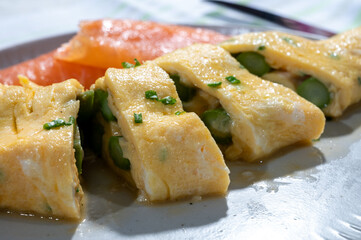 Chicken eggs omelette stuffed with green asparagus with smoked salmon fish, french cuisine, close up