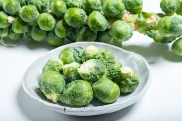 Fototapete Green brussels sprouts on stalk on white table © barmalini